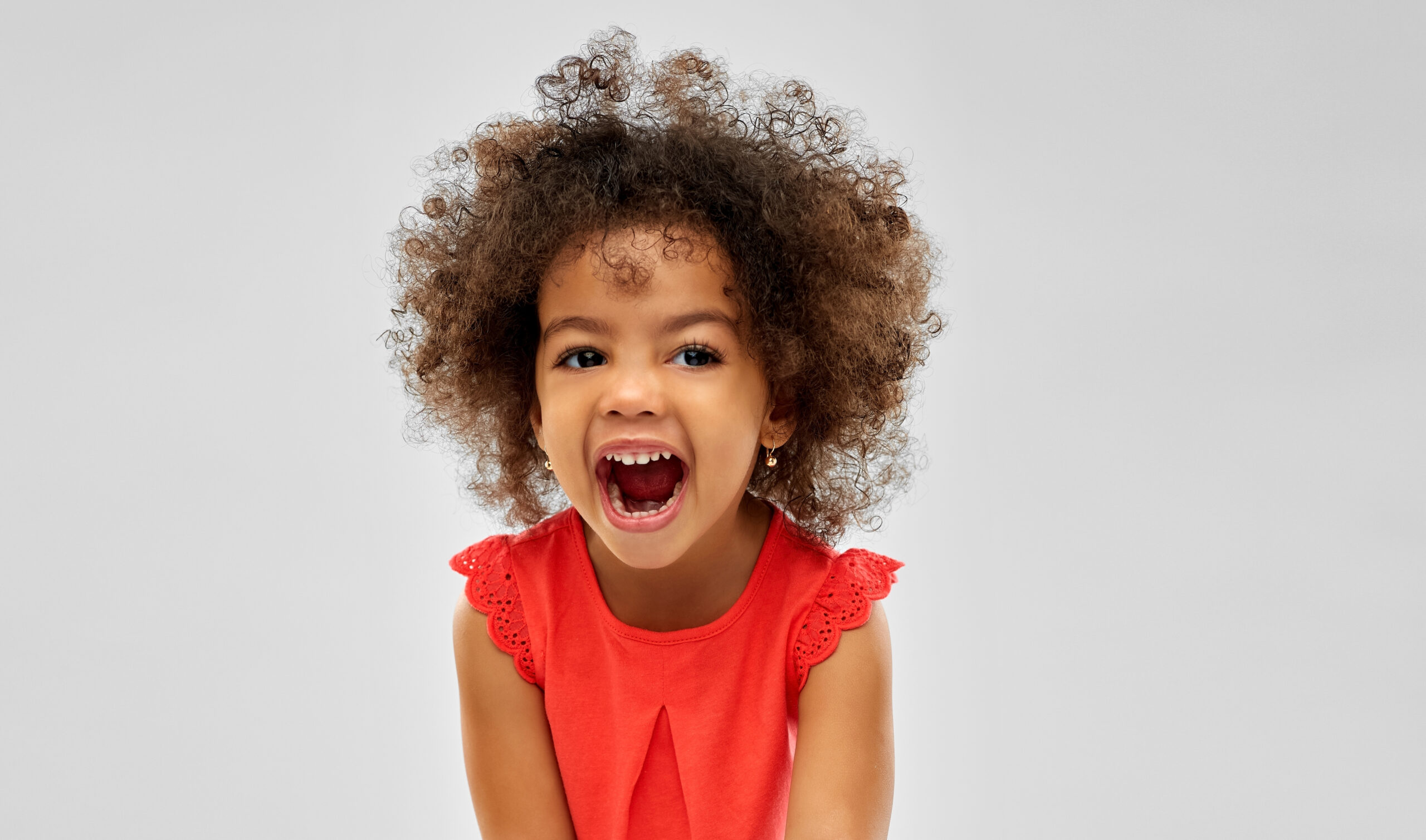 emotion, childhood and expression concept - happy laughing little african american girl over grey background